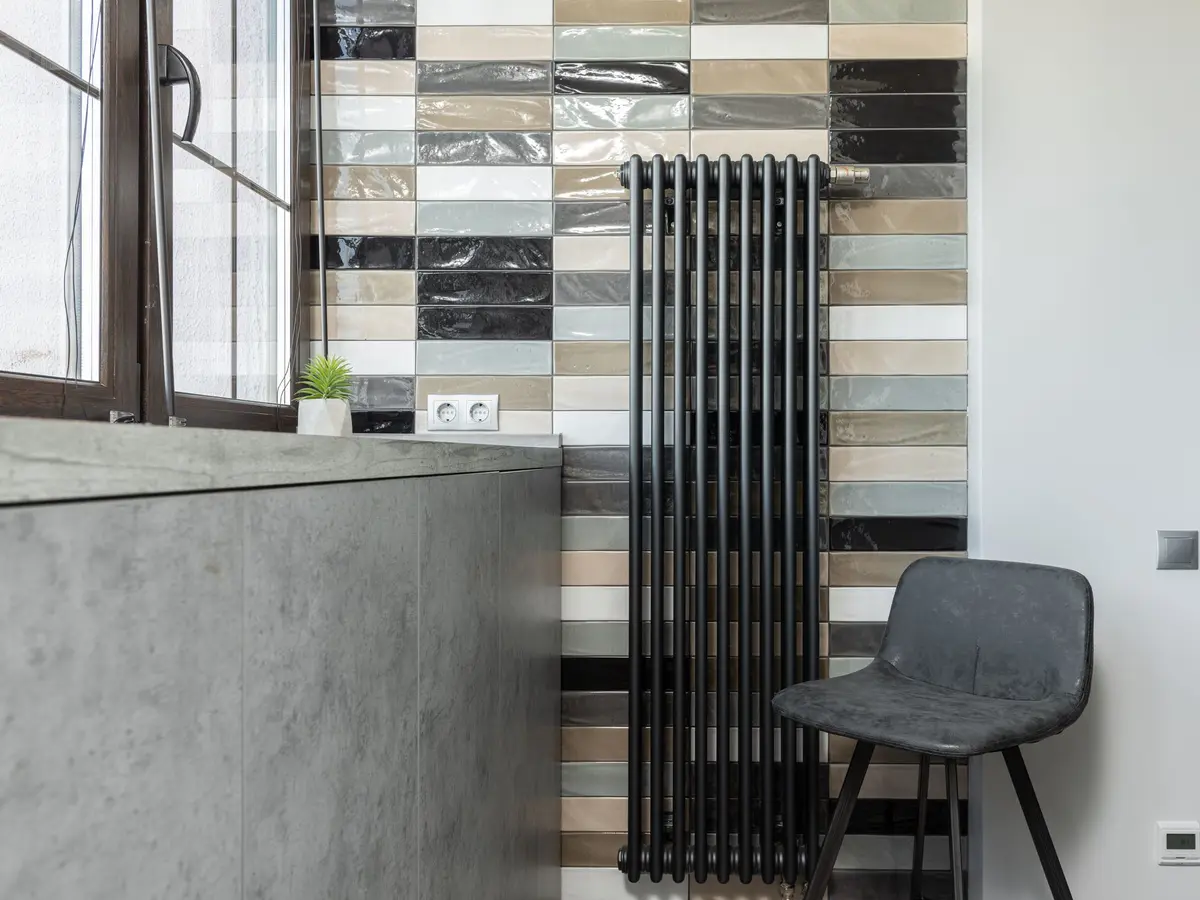 Corner of a room with a concrete-effect wall, a tiled wall and a chair