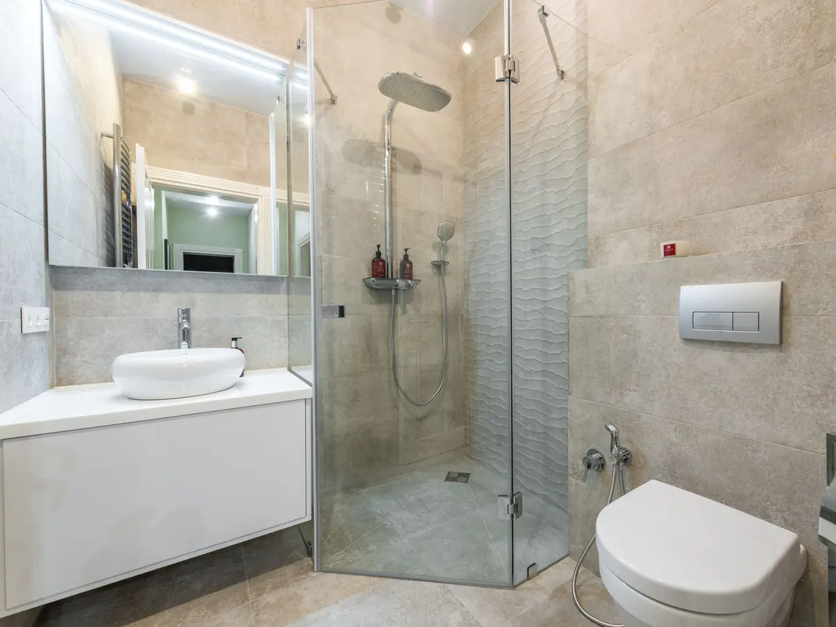 Bathroom with stone-effect walls and a glass shower screen