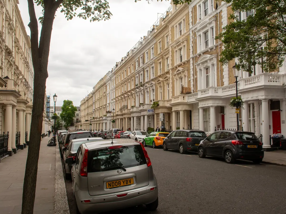Street of cream rendered terraced houses with cars parked along the kerb