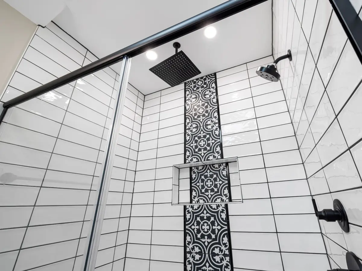 White tiled shower with a patterned tile strip